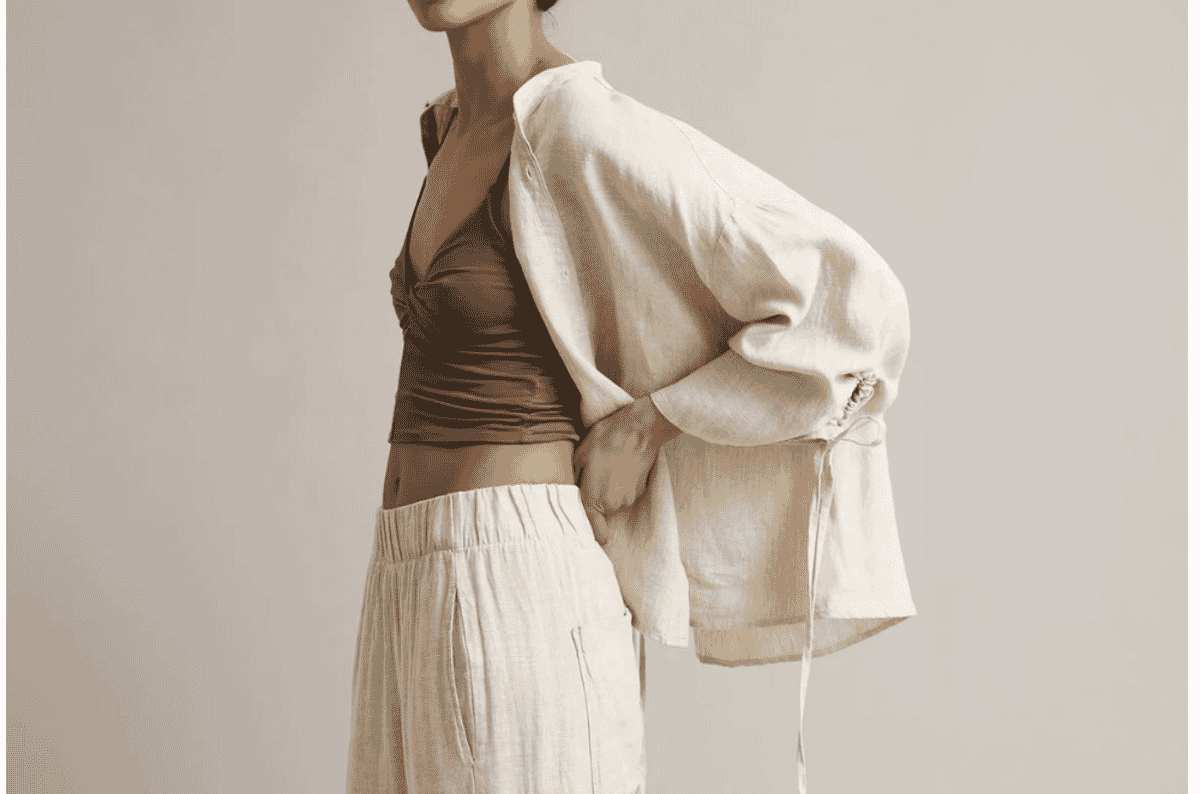 A model in a loose cream overshirt and wide drawstring trousers worn over a fitted brown top, showing the relaxed loungewear silhouette this fabric category is used for.