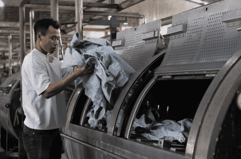 Worker loading denim into an industrial wash machine