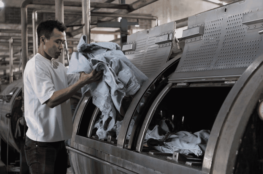 Worker loading denim into an industrial wash machine