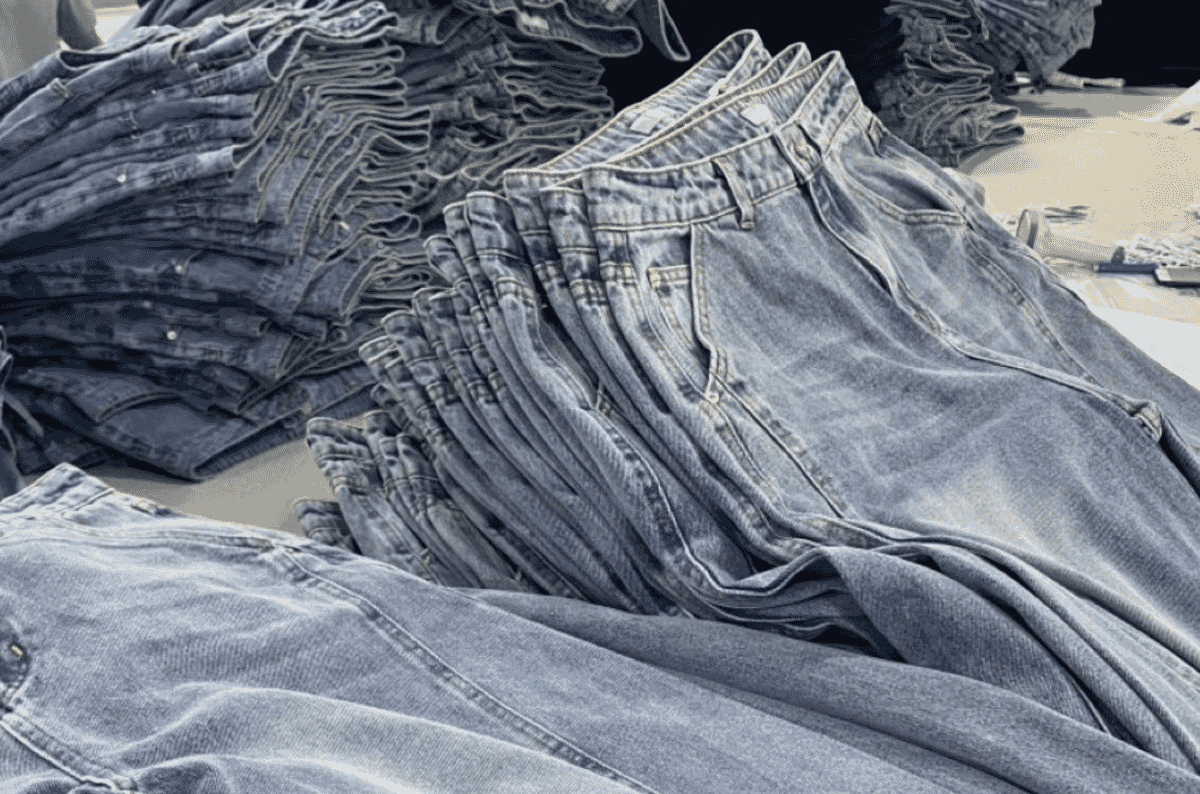 Stacks of finished light-wash jeans folded at the waistband, showing even fading across the thighs and seats.