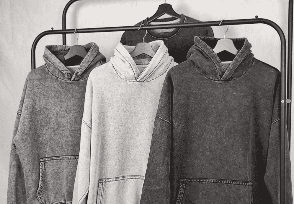 Close-up detail of a heavyweight cotton hoodie with a marbled acid wash finish showing high contrast between faded and untouched areas across the front panel.