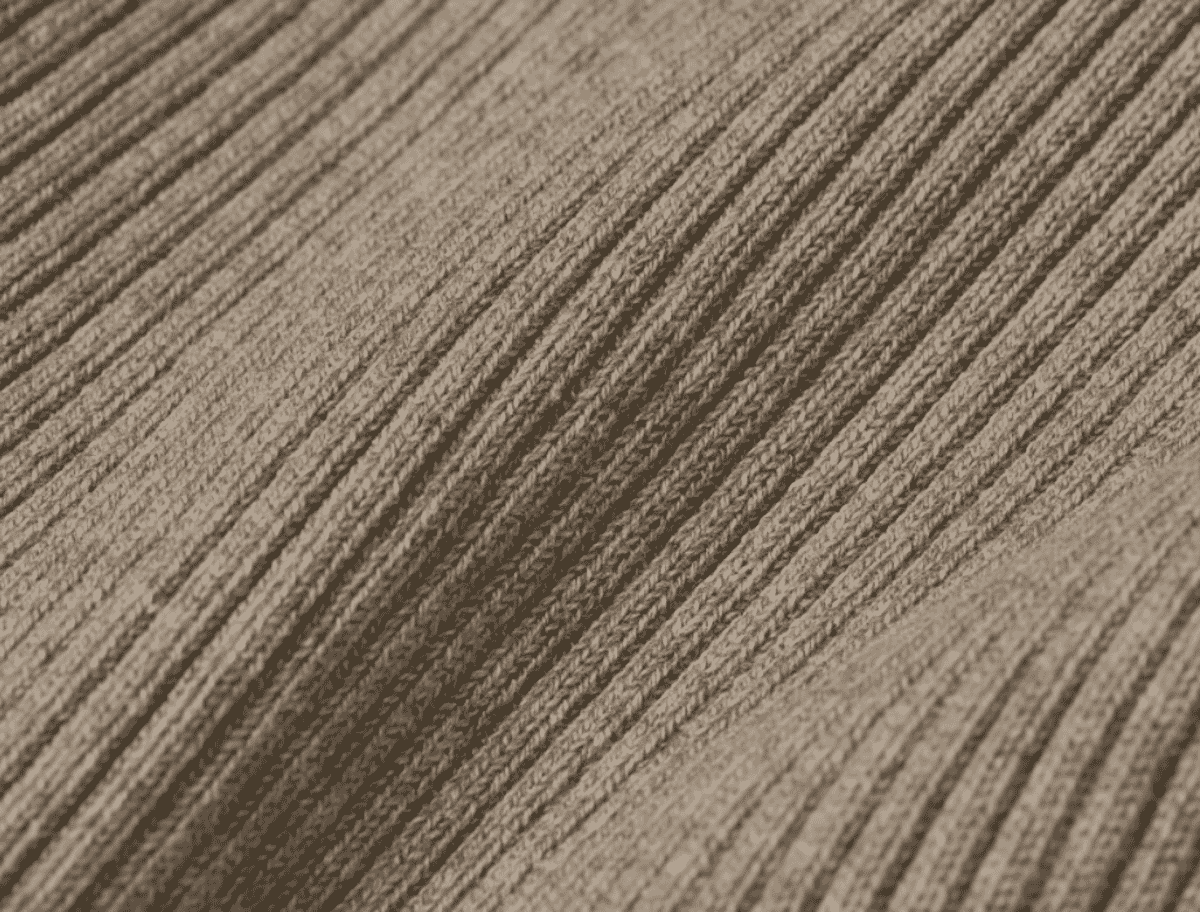 Ribbed cotton knit fabric folded on a Portuguese factory table, showing the vertical wale structure typical of a 2x2 rib construction.