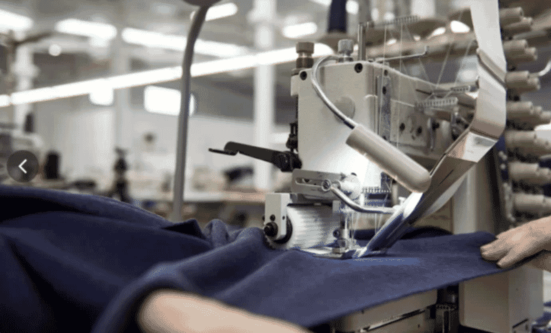 Peça de malha azul-marinho a passar na máquina de costura