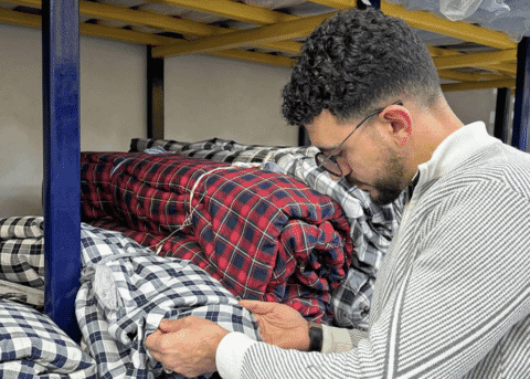 Checking rolls of checked flannel fabric on a storage rack before cutting