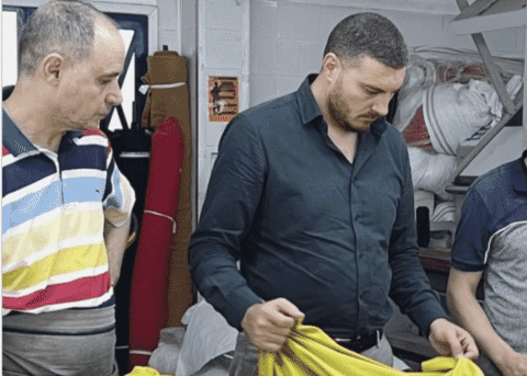 Two people reviewing a mustard garment at an inspection table