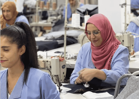 Two machinists at work on a sewing line in blue work coats