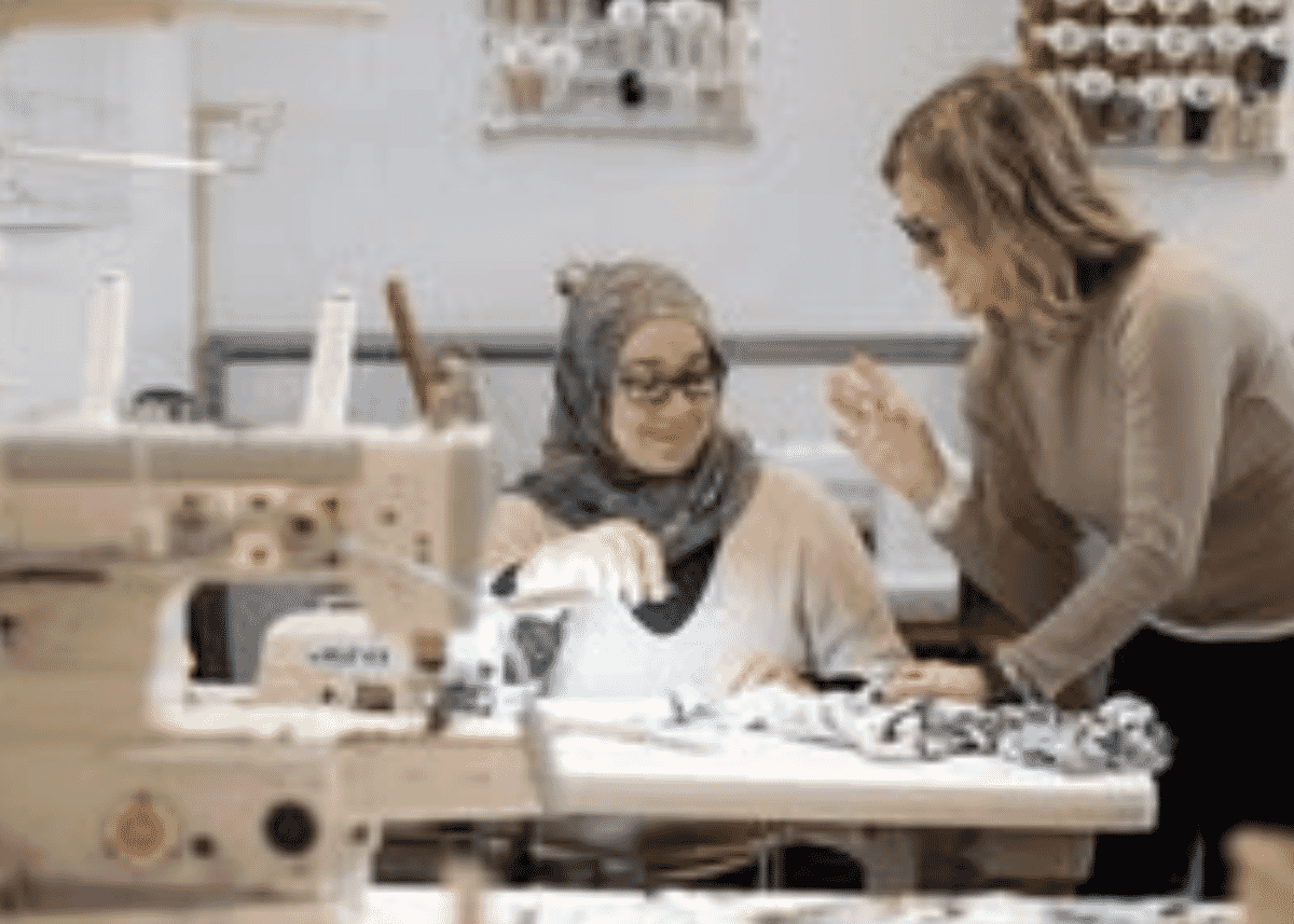 Two women working together at a sewing table in a garment workshop