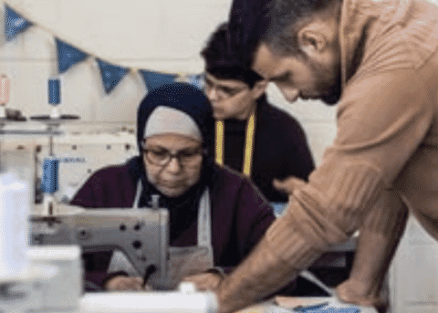 Supervisor leaning in to check a machinist’s work at a sewing station