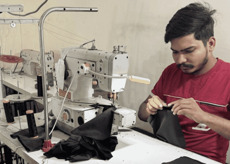 Machinist sewing a black woven garment on a post-bed machine