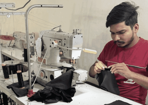 Machinist sewing a black woven garment on a post-bed machine