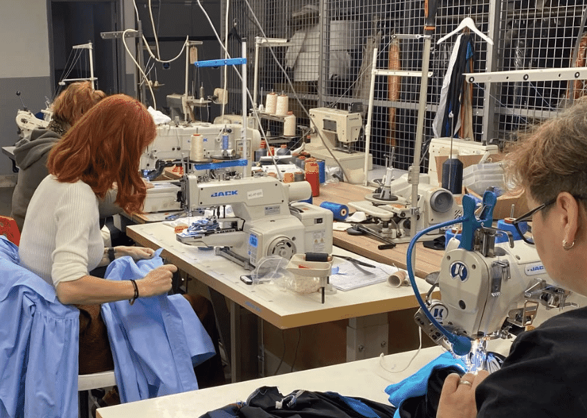Machinists working at industrial sewing machines on a garment factory production line